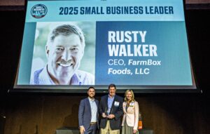 CEO Rusty Walker pictured on stage holding his Small Business Leader Award and standing next to Denver Business Journal Publisher Keith Dennis and Aubrey Ebbs, executive vice president of FirstBank, on May 22, 2025