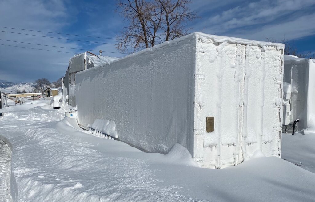 An exterior view of a container farm partially covered in snow.